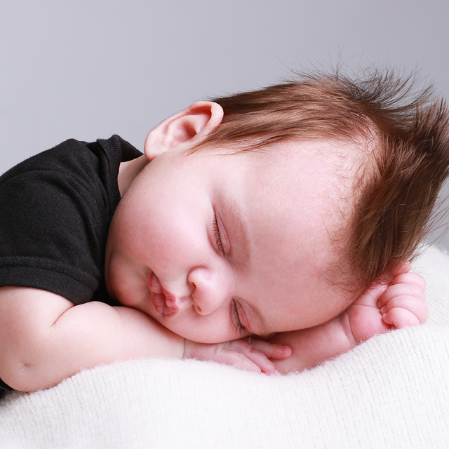 Photo of a newborn sleeping on a fluffy blanket.