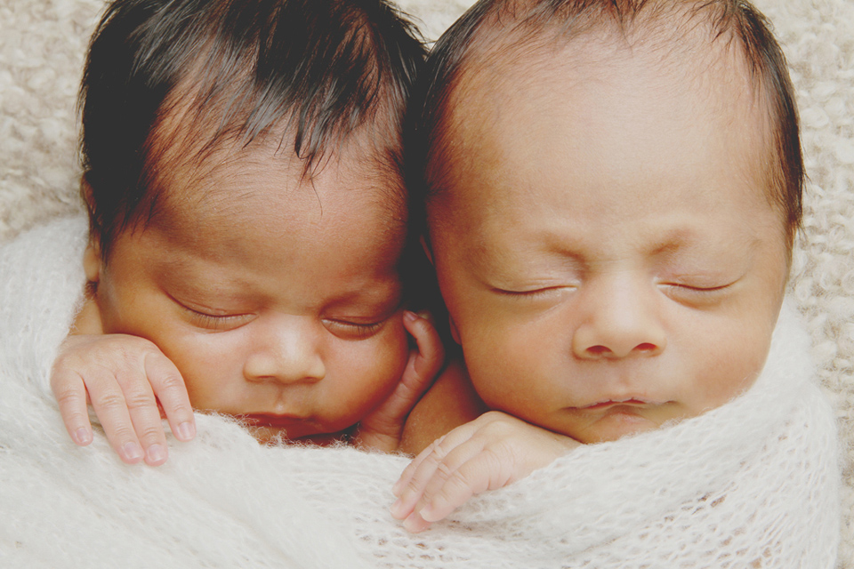 Photo of newborn twins wrapped togheter in a blanket.