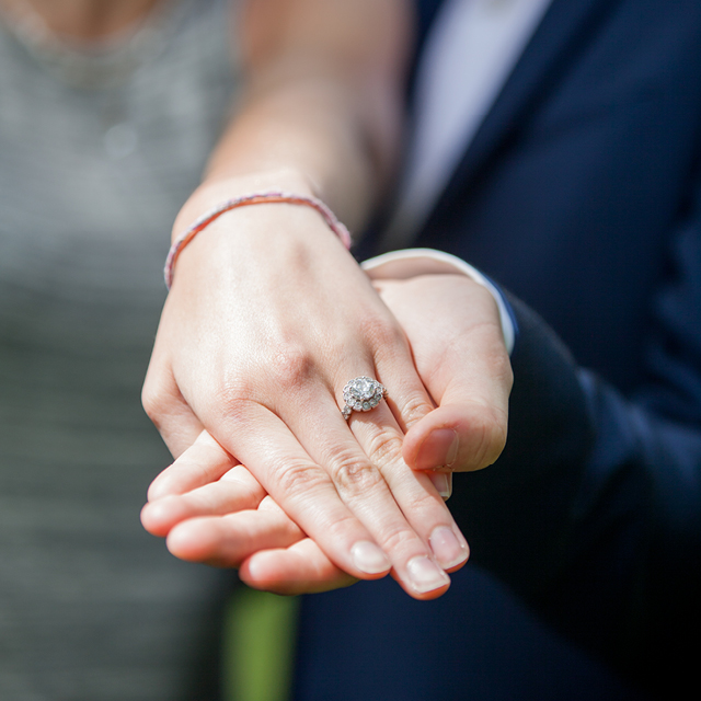 Engagement photo of a couple's hands holding the ring.