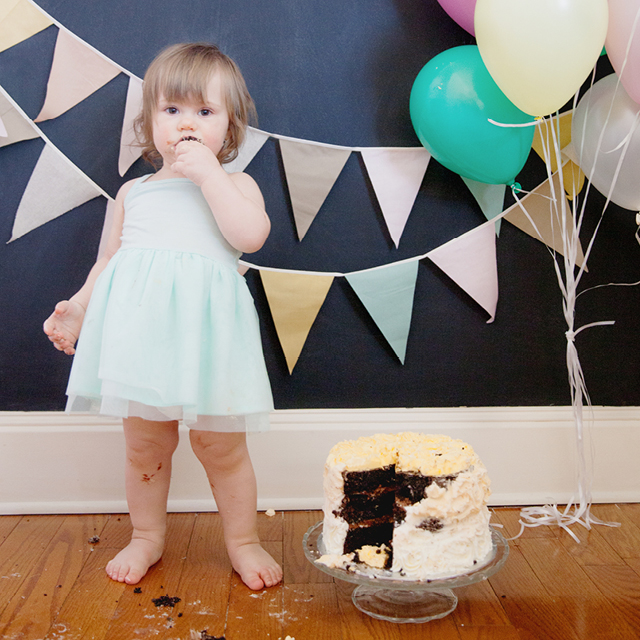 Photo of a baby girl and her cake during a cake smash at home