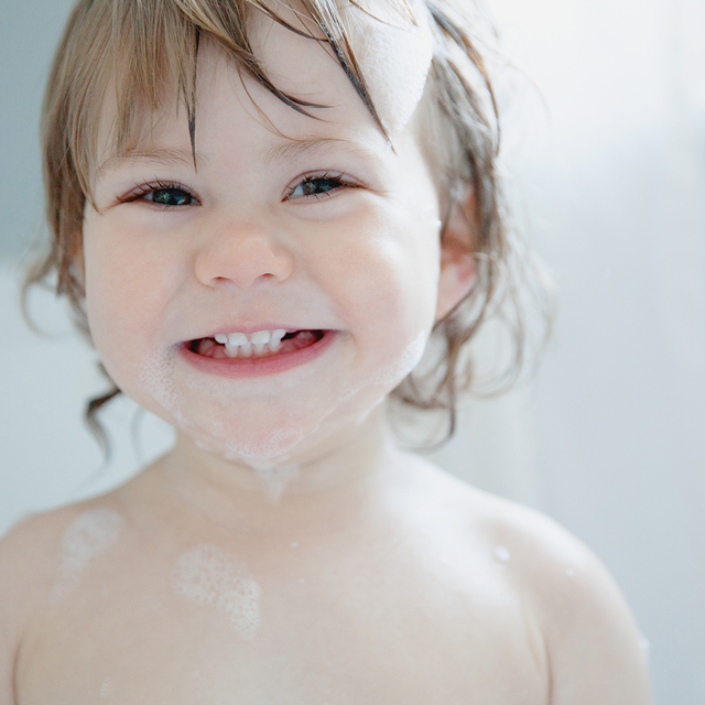 Photo of a smiling little girl in a bubble bath.