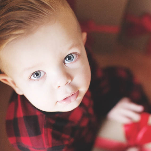 Photo of a little boy in pijama ready to open a christmas gift.