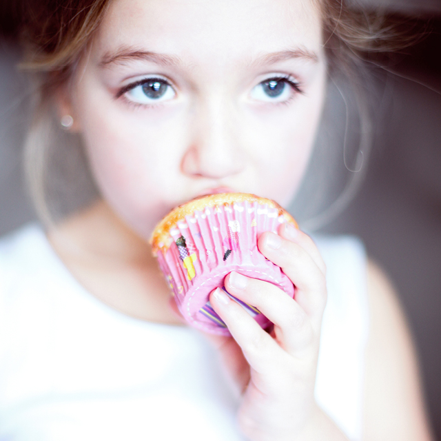 Photo of a child eating a cupcake at home.