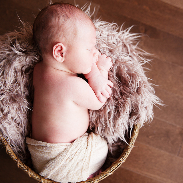Photo of a newborn lying in a wicker basket.