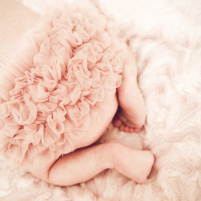 Photo of the pink tutu of a newborn lying in bed.