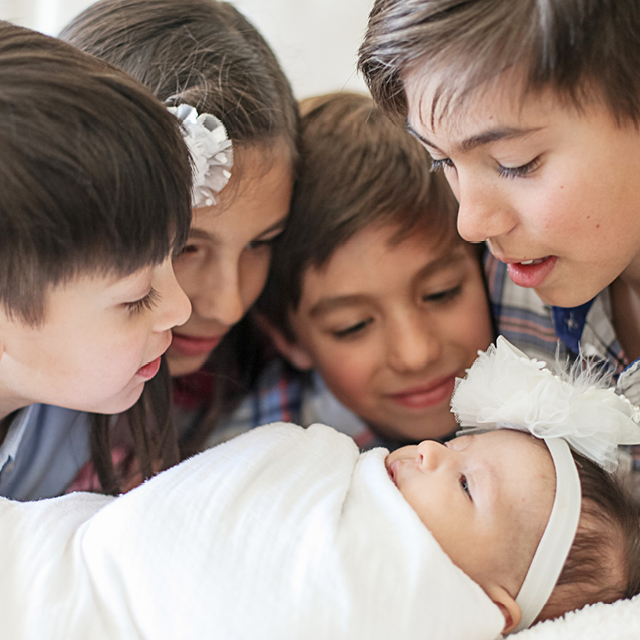 Photo at home of children gathered around a newborn.