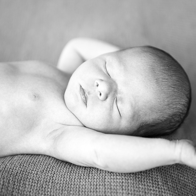 Black and white photo of a newborn child sleeping on the couch.