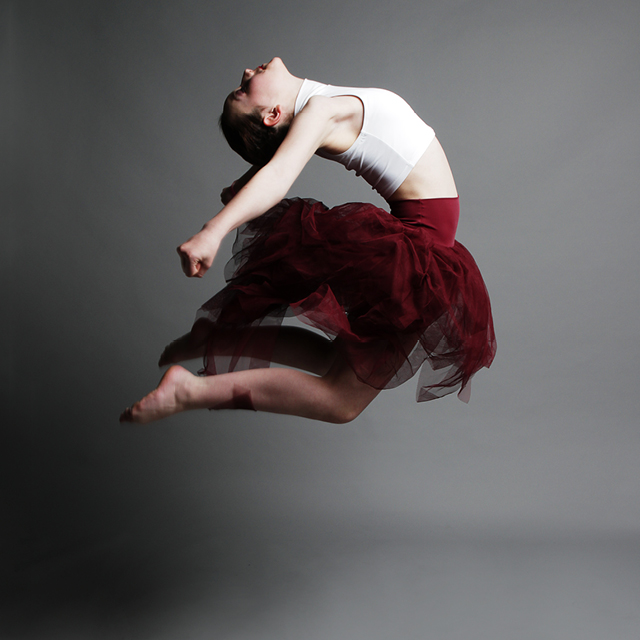 Photography on a grey backdrop of a young dancer performing a jump.