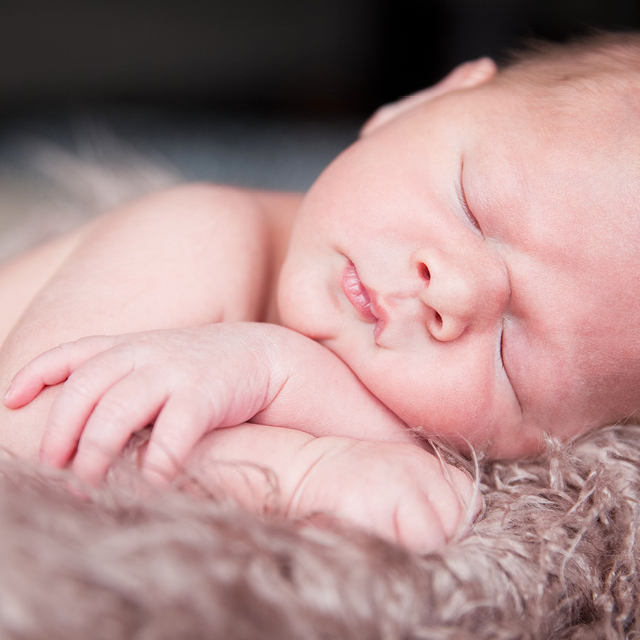 Photo à la maison d'un nouveau-né endormi les bras croisés.