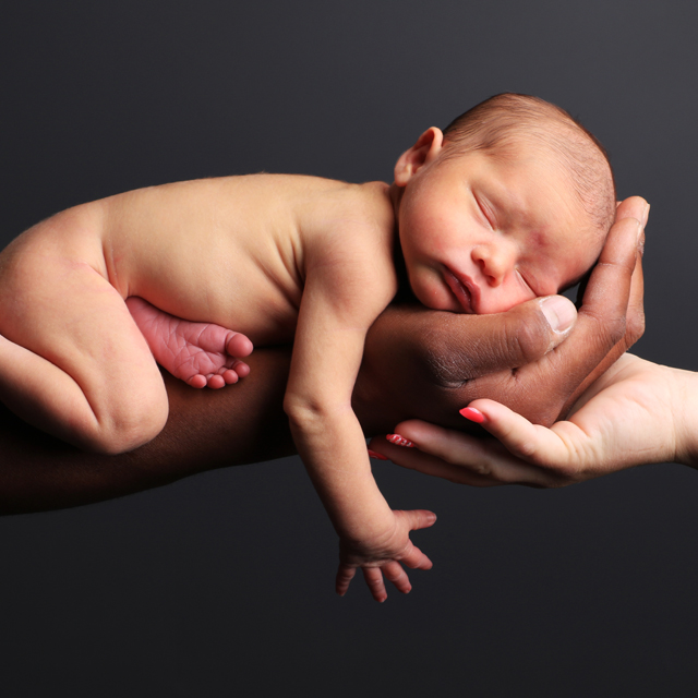 photographie d'un bébé dormant dans les mains de ses parents